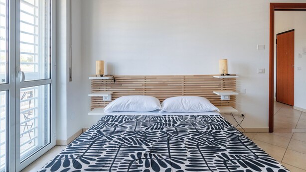 Une chambre à coucher avec un lit, une fenêtre, une table de chevet et une porte.