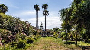 A garden with palm trees, flowering bushes, and a gazebo. - Il Cancello sul Mare by Wonderful Italy (Avola)
