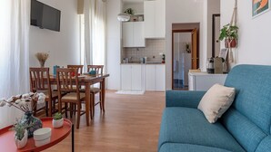 A modern living room with a blue sofa and wooden dining table with chairs.