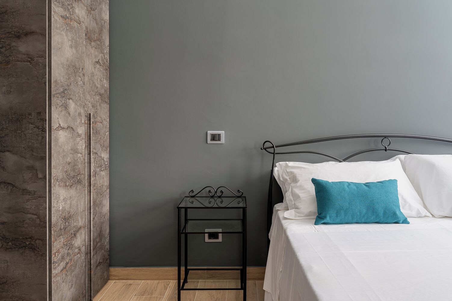 Un dormitorio con una cama, una mesita de noche y una pared con textura.