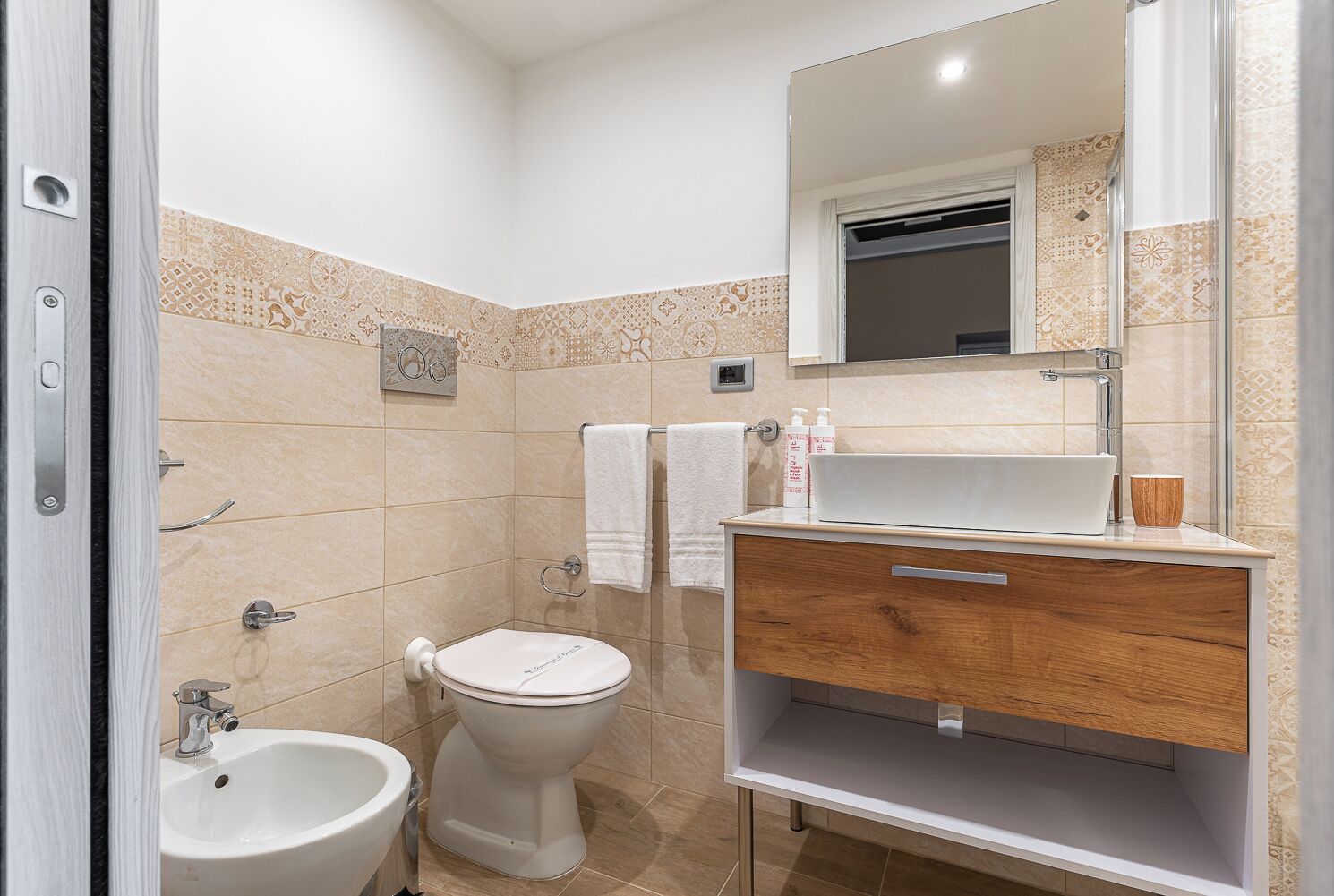A modern bathroom with a toilet, bidet, sink, and vanity.