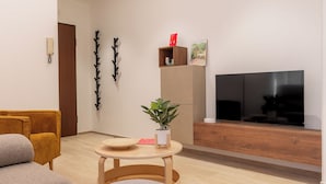 A modern living room with a sofa, a coffee table, a TV, and a plant. - Teocrito Apartment by Wonderful Italy (Syracuse)