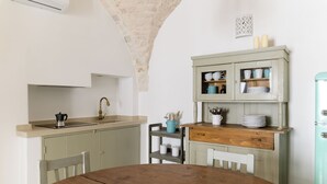 A kitchen with a wooden table, a sink, and a cabinet with dishes. - Casetta Wilma by Wonderful Italy (Cisternino)