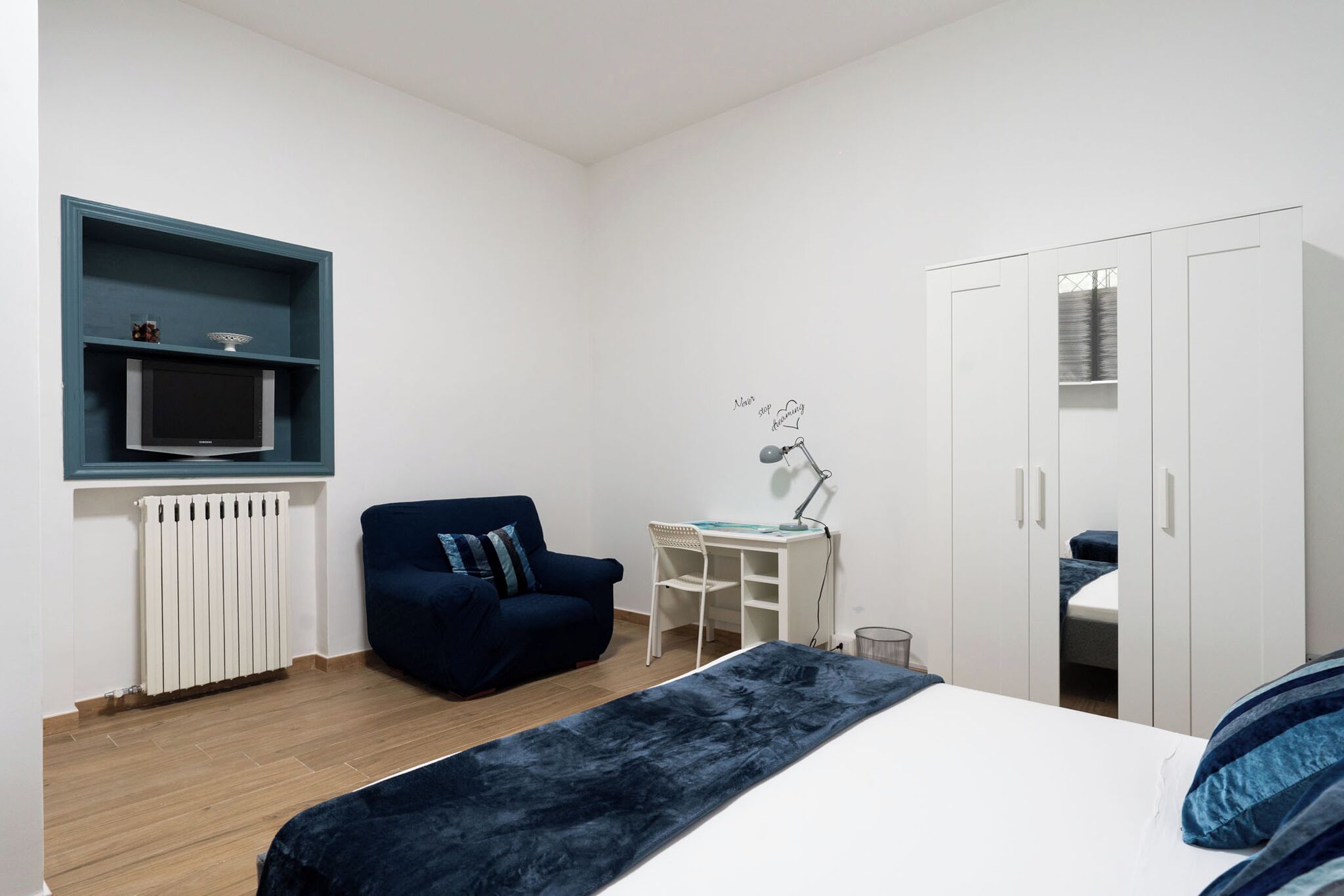 Une chambre à coucher comprenant un lit, un bureau, une chaise, une armoire et un radiateur.