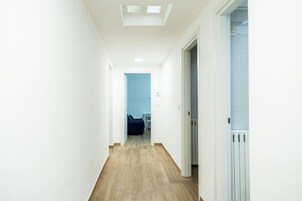 Un pasillo estrecho con suelo de madera y paredes blancas.