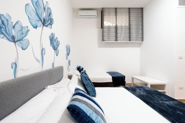 A modern bedroom with a bed, a bedside table, and a window with blinds.