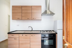 Una cocina moderna con armarios de madera, una campana extractora de acero inoxidable, un fregadero, una estufa y un horno.