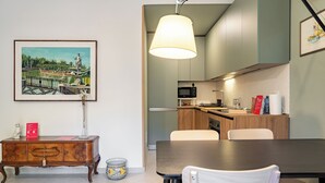 A dining area with a table and chairs, a cabinet with a decorative item, and a painting on the wall. - Casa Gianna by Wonderful Italy (Syracuse)