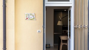 An open doorway leading to a room with a chair and a lamp. A sign with text is visible on the wall. - Casa Gianna by Wonderful Italy (Syracuse)