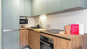 A modern kitchen with wooden cabinets, a built-in oven, a microwave, and a coffee machine. - Casa Gianna by Wonderful Italy (Syracuse)
