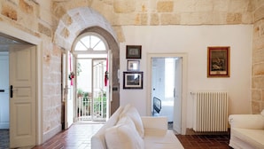 Un salon spacieux avec un canapé blanc, des murs en pierre et un sol carrelé.