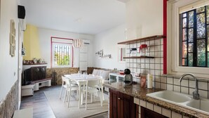 A modern kitchen with a dining area, featuring a granite countertop, a sink, and a window with a view.