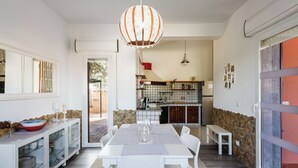A modern kitchen with a stone accent wall, a dining area with a white table and bench, and a hanging light fixture.