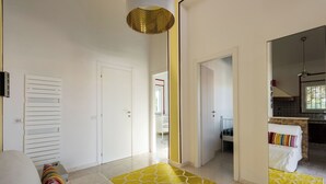 A bedroom with a bed, a yellow patterned rug, and a white door.
