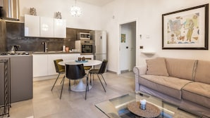 A modern kitchen with white cabinets, a dining table with chairs, and a glass coffee table. - Nicu Amuri con Terrazza a Noto by Wonderful Italy (Noto)