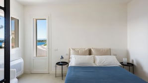 A bedroom with a bed, a nightstand, a lamp, and a view of the sea. - Villa Plemmiria by the Sea by Wonderful Italy (Syracuse)