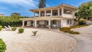 A two-story house with a covered patio, outdoor seating, and a gravel driveway. - Villa Plemmiria by the Sea by Wonderful Italy (Syracuse)