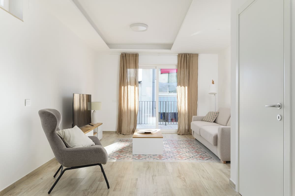 Een moderne woonkamer met een bank, fauteuil, televisie en een kamerbreed tapijt.