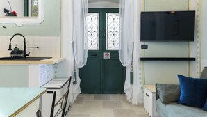 A compact kitchen with a sink, a small table, and a green door with white curtains. - Casa del Polpo Blu by Wonderful Italy (Ostuni)