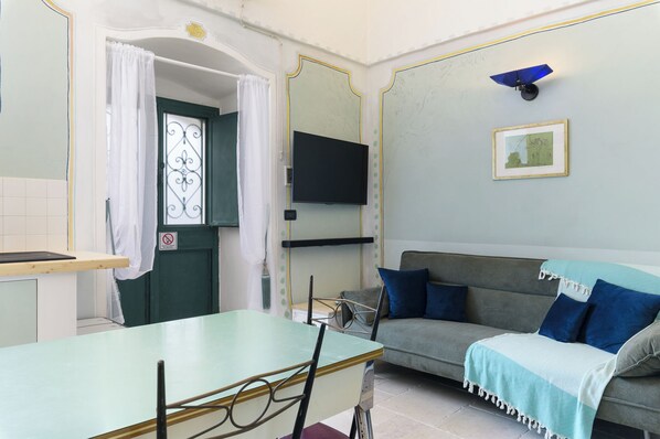 Una habitación con una mesa de comedor, un sofá y un televisor montado en la pared.