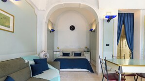 A room with a bed, a sofa, a table, and chairs. - Casa del Polpo Blu by Wonderful Italy (Ostuni)