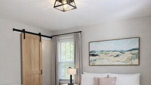 Une chambre à coucher avec un lit, une table de chevet, une lampe, une armoire et un tableau au mur.
