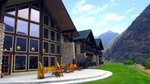 A lodge with a stone facade, large windows, and a patio area with outdoor seating. - Riverfront 1 Bedroom Suite at Salmon Rapids Lodge (Riggins)