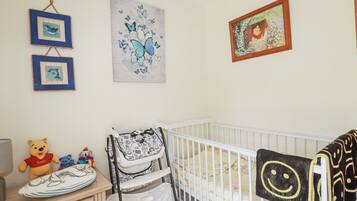 Une chambre de bébé avec un berceau, une table à langer et des décorations murales, notamment des tableaux encadrés et un ours en peluche à l’effigie de Winnie l’ourson.