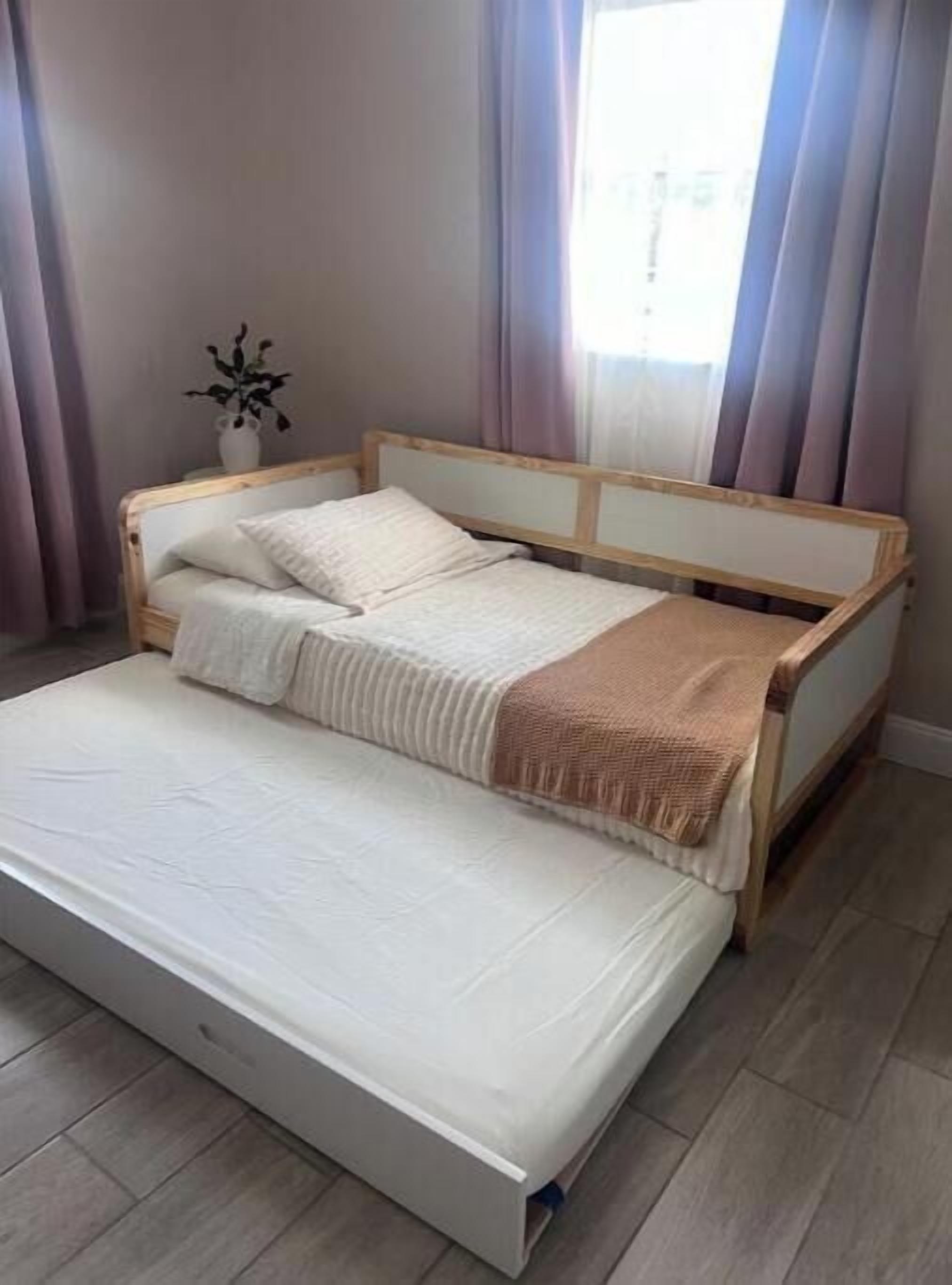 Una cama individual con estructura de madera y colchón blanco.