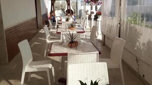An outdoor patio with white tables and chairs, potted plants, and hanging flower baskets. - La Scogliera Hotel Boutique (Rodi Garganico)