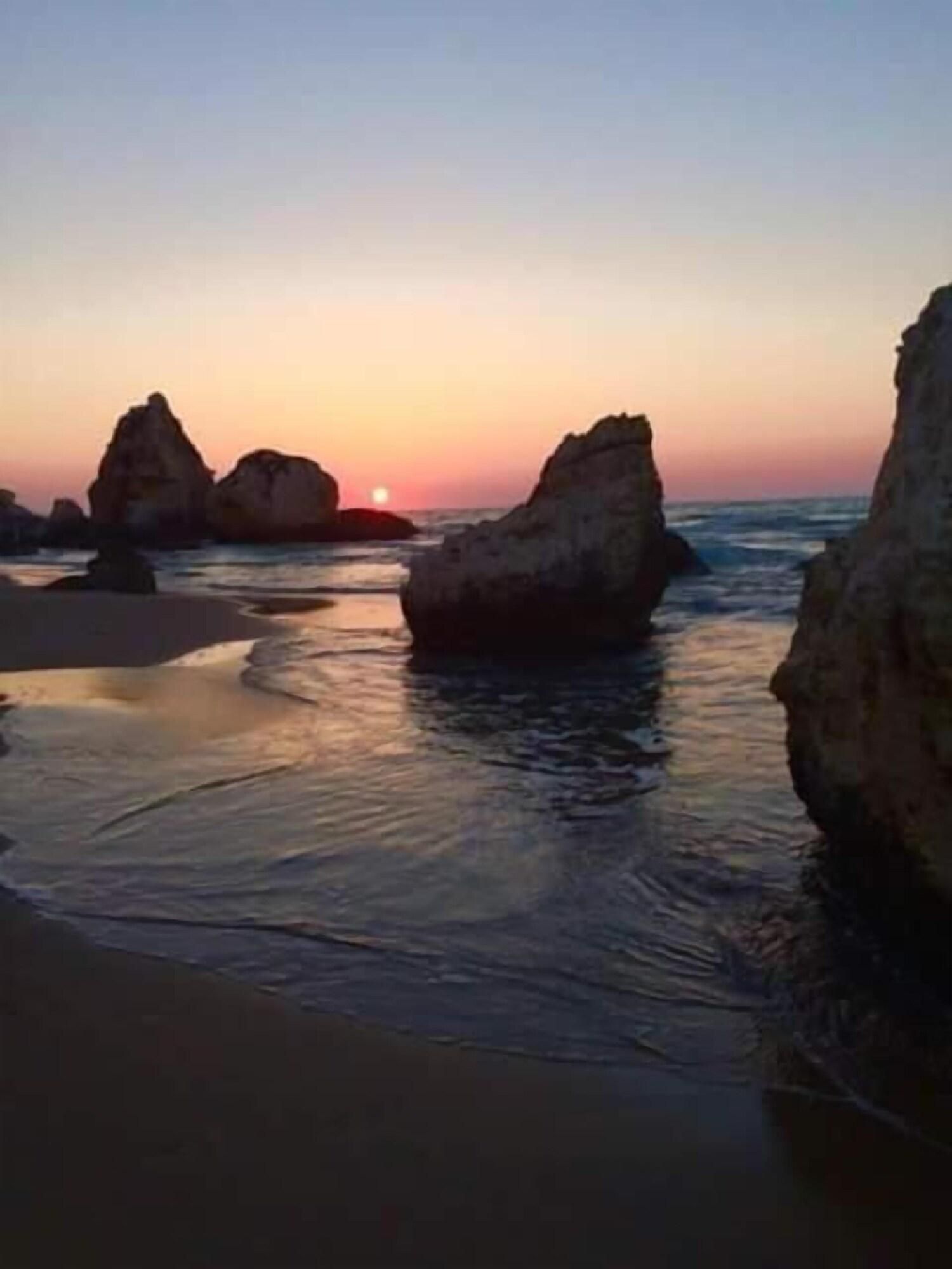 Une plage avec de grandes formations rocheuses et une eau calme.
