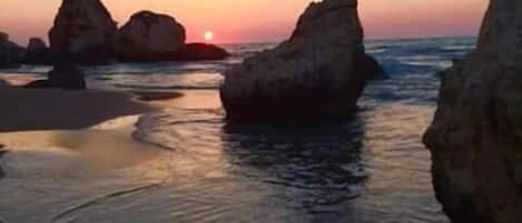 A beach with large rock formations and calm water.