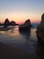Una playa con grandes formaciones rocosas y agua tranquila.