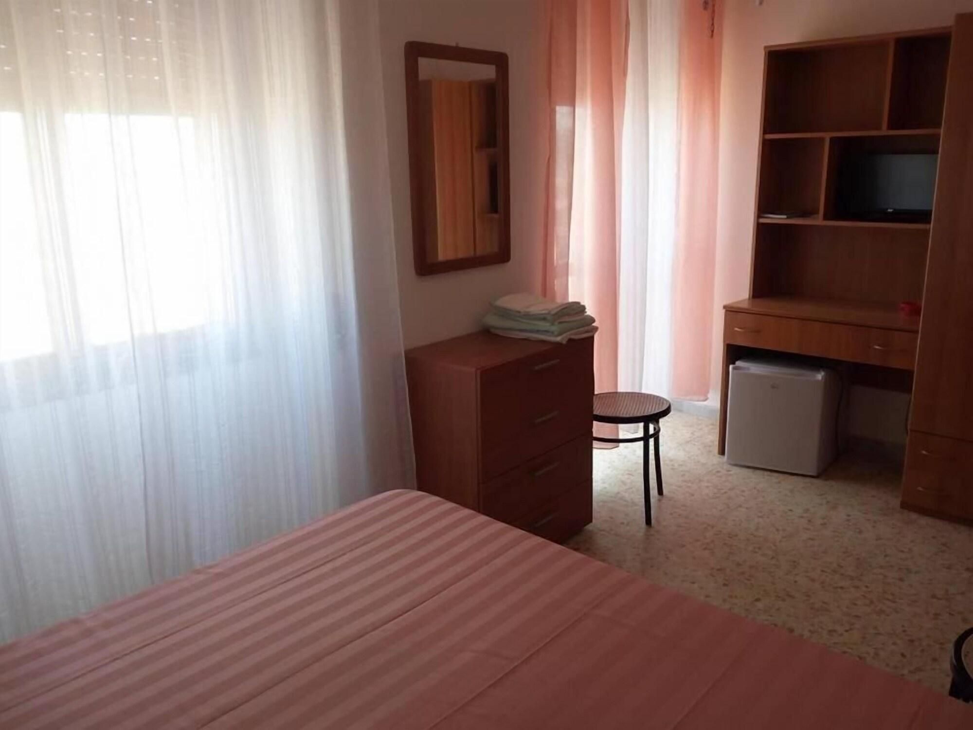 Un dormitorio con cama, cómoda, escritorio con computadora y silla.