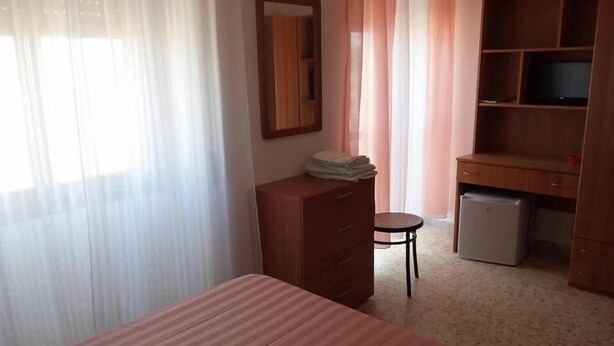 A bedroom with a bed, a dresser, a desk with a computer, and a chair. - La Scogliera Hotel Boutique (Rodi Garganico)