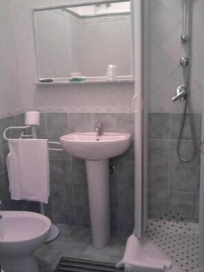 A bathroom with a pedestal sink, a toilet, a shower, and a mirror. - La Scogliera Hotel Boutique (Rodi Garganico)