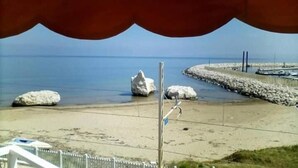 A beach with large rocks, a paved walkway, and a distant view of the sea. - La Scogliera Hotel Boutique (Rodi Garganico)