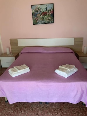 Ein Schlafzimmer mit einem Bett, zwei Nachttischen, einem Gemälde und Handtüchern.