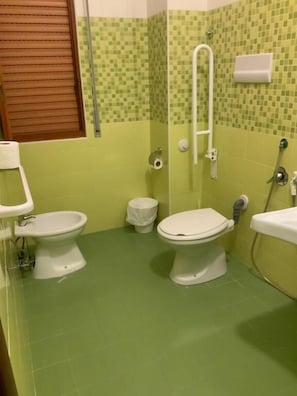 A bathroom with two toilets, a shower, and a sink.