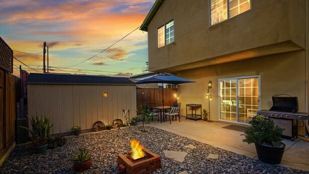 Un patio trasero con una chimenea, mobiliario de exterior y una parrilla.