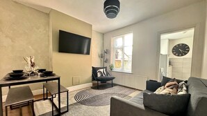 Ein modernes Wohnzimmer mit einer Couch, einem Couchtisch und einem an der Wand montierten Fernseher.