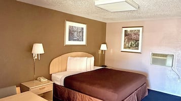 Quarto de hotel com cama, mesas de cabeceira, luminárias e escrivaninha com cadeira.