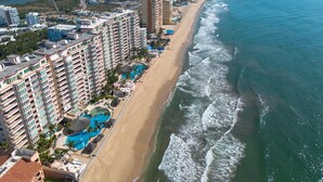 A coastal hotel with multiple high-rise buildings, a beachfront, and a swimming pool area.