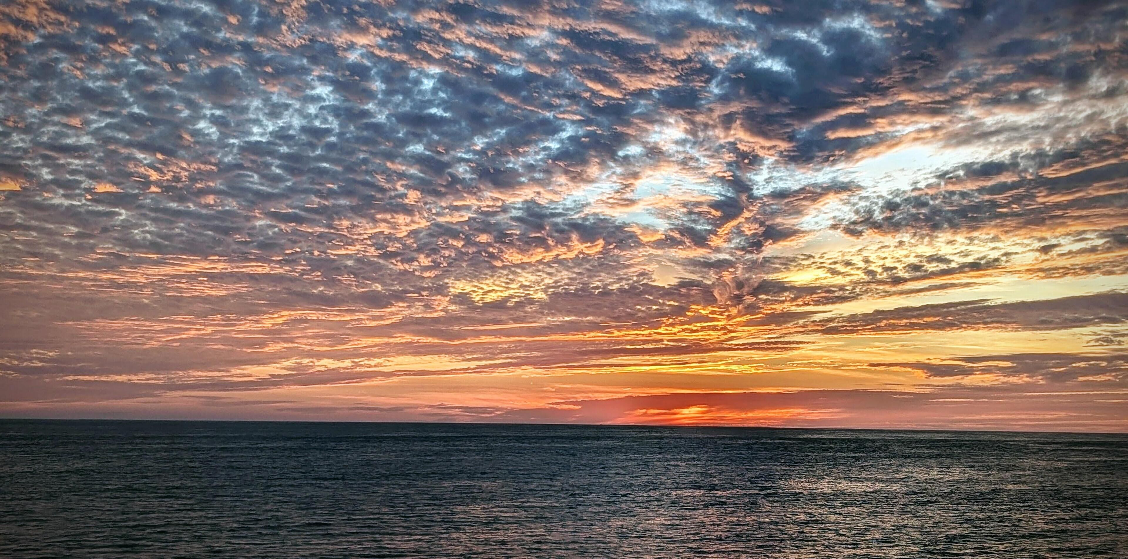 A sunset over the ocean with a clear sky.