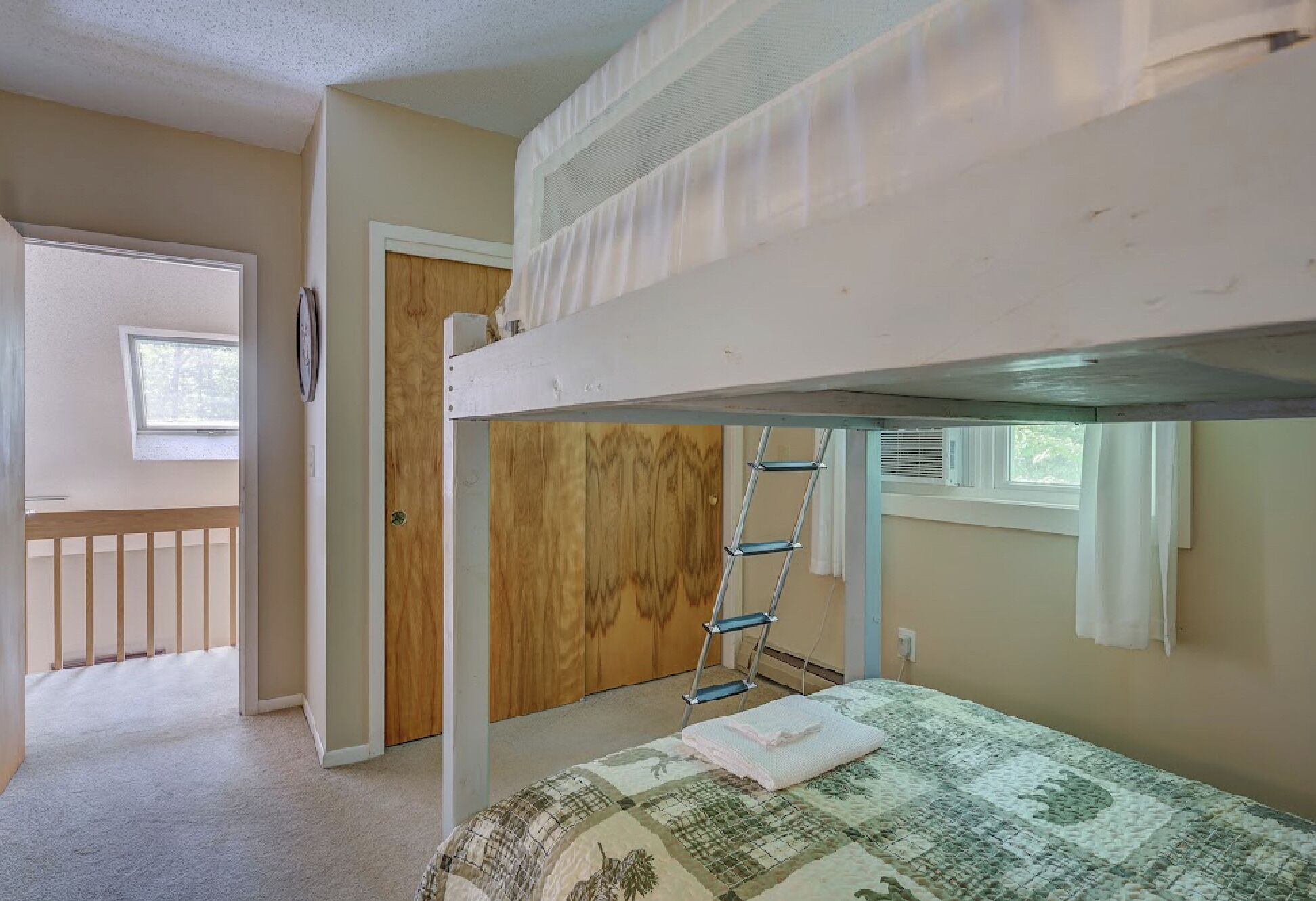 A bunk bed room with a ladder, a door, and a window.