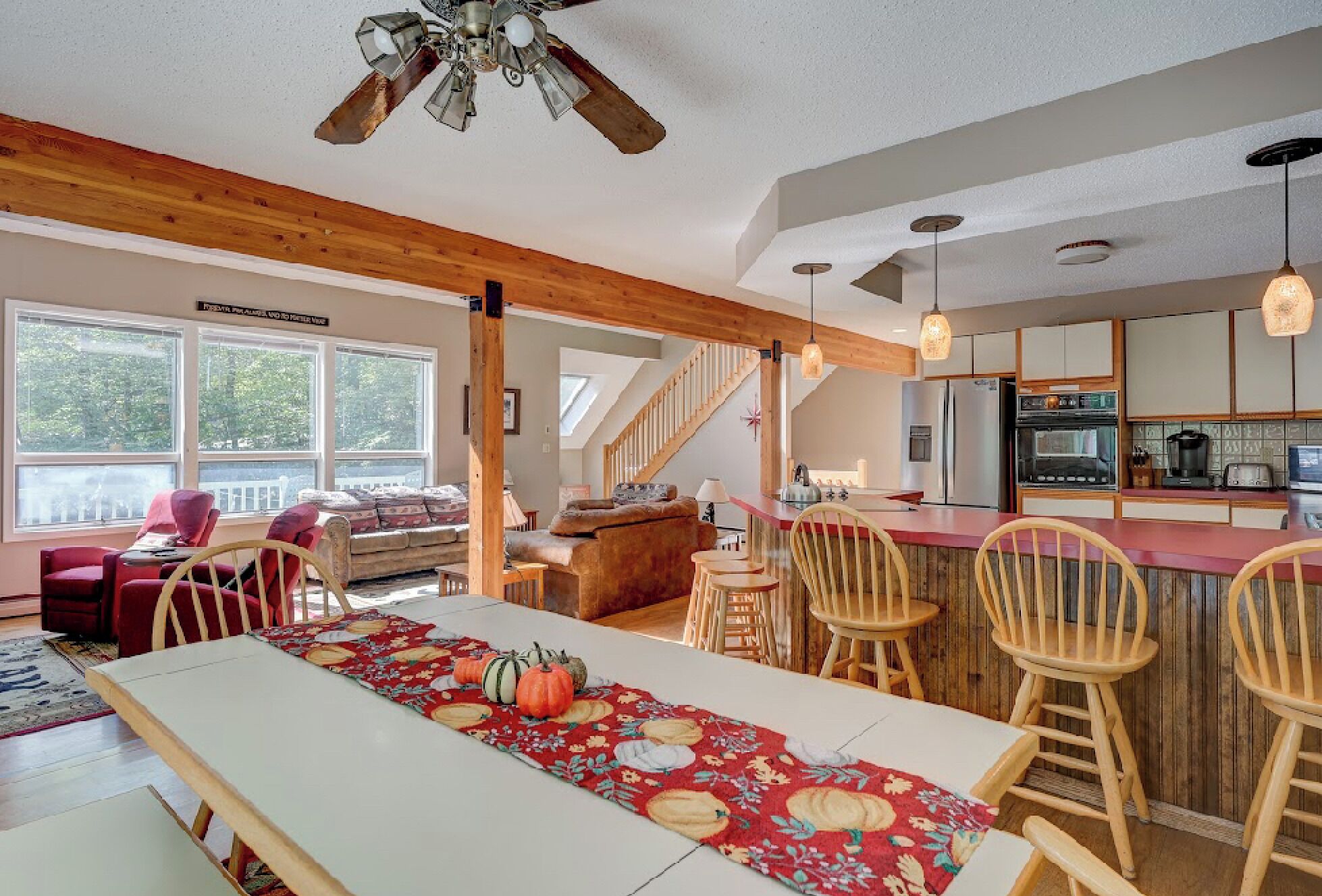 A spacious living area with a dining table, wooden chairs, and a kitchen in the background.