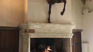A fireplace with a horse sculpture above it, logs in front, and a wooden door to the left. - Reception hall Champs Forts (Saint-Aoustrille)
