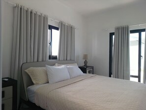A bedroom with a bed, curtains, a nightstand, and a lamp. - Modern 3 BR Villa w/ pool in gated community (Sosúa)