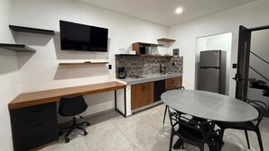 Cozinha moderna com bancada de madeira, forno embutido, frigorífico e área de jantar com mesa e cadeiras.