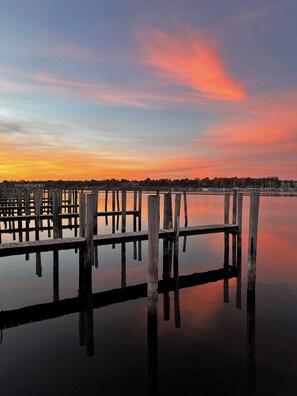 Een houten steiger die zich uitstrekt over kalm water, met een zonsondergang op de achtergrond.